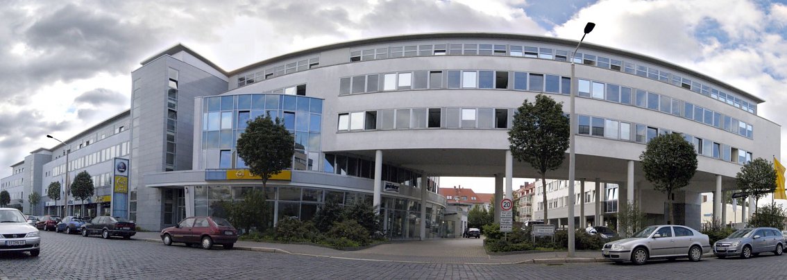  Gro&szlig;es, modernes Autohausgeb&auml;ude der Autohaus-Peter-Gruppe in der Schlachthofstra&szlig;e 80 in Erfurt mit abgerundeter Glasfassade, mehreren Etagen und markanten B&auml;umen vor dem Geb&auml;ude. Autos parken auf dem Vorplatz und an der Stra&szlig;e.