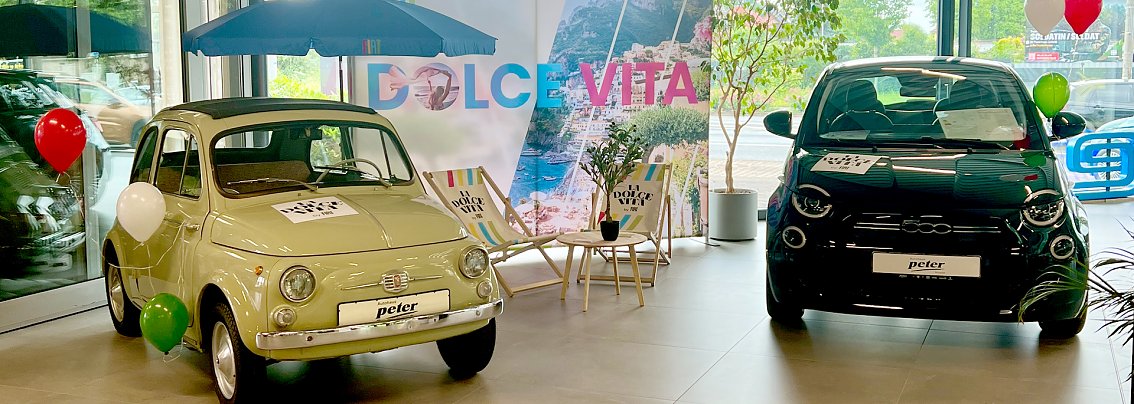 2 Fiats mit Luftballons im Showroom vor einer bunten "La Dolce Vita"-Wand.

