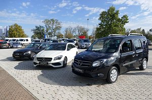 Mehrere schwarze und wei&szlig;e Mercedes �Junge Sterne� Gebrauchtwagen, darunter Limousinen und ein Hochdachkombi, auf einem gepflasterten Autohaus-Areal bei sonnigem Wetter.
