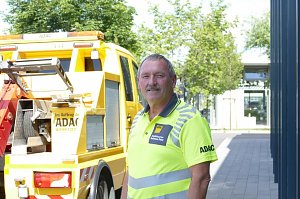 Matthias K&ouml;hler, Mitarbeiter des Autohaus Peter als ADAC Mobilit&auml;tspartner, steht in leuchtend gelber Dienstkleidung mit ADAC-Logo vor einem gelben ADAC-Pannenhilfefahrzeug. Im Hintergrund B&auml;ume und ein moderner Geb&auml;udeeingang.