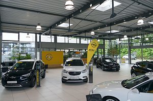 Innenansicht eines modernen Opel-Autohauses mit mehreren ausgestellten Fahrzeugen, darunter Crossland X und Mokka X, viel Tageslicht durch große Fensterflächen, sowie gelbe Opel- und Peter-Markenschilder.