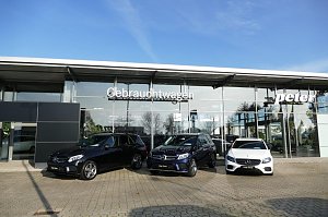 Glasfassade des Autohauses Peter mit der Aufschrift �Gebrauchtwagen�. Davor stehen drei Mercedes-Modelle: zwei schwarze SUVs und ein wei&szlig;er Kombi, alle mit dem Schild �Junge Sterne�. Blauer Himmel, Spiegelungen von B&auml;umen und Umgebung in den Glasfl&auml;chen.
