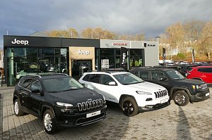 Jeep-, Dodge- und RAM-Autohaus mit moderner Glasfassade in Nordhausen, davor mehrere geparkte Jeep-Fahrzeuge in Schwarz und Wei&szlig; auf gepflastertem Hof.