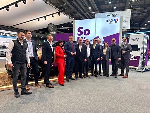 Eine gro&szlig;e Gruppe von M&auml;nnern und einer Frau posiert gemeinsam f&uuml;r ein Foto vor einem Stand der Firma TEAG Mobil auf der Automobilmesse Erfurt 2025. Im Hintergrund sind ein Elektroauto, ein Ladeger&auml;t und Werbebanner zu sehen.