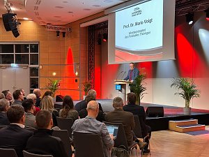 Prof. Dr. Mario Voigt spricht am Rednerpult der Messe Erfurt, im Hintergrund eine Leinwand mit seinem Namen und Titel als Ministerpr&auml;sident Th&uuml;ringens.