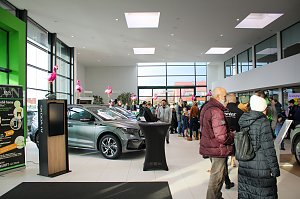Gro&szlig;er Ausstellungsraum mit neuen �koda-Fahrzeugen. Viele Menschen gehen durch die Halle. Rosa Flamingos sind als Dekoration aufgestellt.