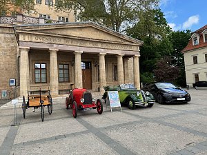 Oldtimeraufstellung vor S&auml;ulenfassade: Die gleichen vier Fahrzeuge sind vor dem klassizistischen Eingangsportal des Geb&auml;udes in einer Reihe geparkt. Ein Aufsteller mit Veranstaltungsinfos steht vor dem gr&uuml;nen Cabrio.