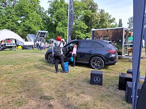 SUV mit Besuchern: Schwarzer Mercedes-Benz SUV, in den eine Frau mit Kind hineinschaut, umgeben von weiteren Ausstellungsfl&auml;chen.