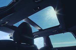 Panoramadach: Blick aus dem Innenraum des Mitsubishi Outlander auf das ge&ouml;ffnete Panoramadach mit Sonnenlicht und blauem Himmel.