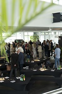 Blick in den Ausstellungsraum des Autohauses Peter beim s&uuml;dafrikanischen Abend in Heiligenstadt. Zahlreiche G&auml;ste stehen in Gruppen zusammen, unterhalten sich und genie&szlig;en die entspannte Atmosph&auml;re zwischen dekorierten Stehtischen und Fahrzeugen.