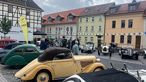 Mehrere Oldtimer stehen auf dem Marktplatz von Sondershausen vor einer H&auml;userzeile mit bunten Fassaden. Zu sehen sind historische Fahrzeuge in verschiedenen Farben und Karosserieformen � unter anderem ein cremefarbenes Cabriolet im Vordergrund. Menschen schlendern zwischen den Autos.