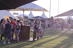 Besucher genie&szlig;en den Abend auf der Wiese beim Reitturnier in Immenrode. Unter gro&szlig;en Sonnenschirmen und Pagodenzelten stehen Gruppen zusammen, einige G&auml;ste sitzen an Stehtischen oder auf B&auml;nken.