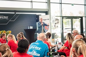 Bodo Ramelow spricht beim Medien-Tag des Th&uuml;ringer HC in Erfurt. Er steht mit Mikrofon in der Hand an einem Stehtisch vor einem Publikum aus Spielerinnen und G&auml;sten, die &uuml;berwiegend rote Shirts tragen. Im Hintergrund Banner mit dem Logo des Th&uuml;ringer HC.