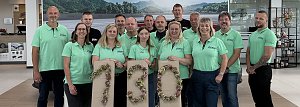 Teamfoto der Skoda Crew in &uuml;berwiegend t&uuml;rkisfarbenen T-Shirts; devor eine 130 aus gebundenen Blumen.