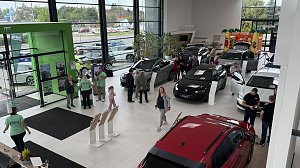 Blick von oben in den Ausstellungsraum des Autohauses Autowelt Peter w&auml;hrend der Jubil&auml;umsfeier zu 130 Jahren �koda. Besucherinnen und Besucher schauen sich verschiedene Fahrzeuge an, Mitarbeitende in gr&uuml;nen Shirts beraten. Im Hintergrund steht eine bunte H&uuml;pfburg f&uuml;r Kinder.