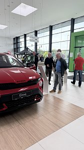 Ein roter �koda Elroq steht im Ausstellungsraum. Mehrere Besucher stehen daneben und informieren sich an den Infostelen.