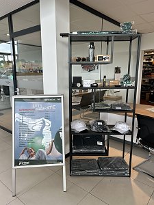 Vitrine mit �koda-Merchandising-Artikeln wie M&uuml;tzen, Flaschen und Accessoires im Autohaus Autowelt Peter. Daneben ein Aufsteller mit der Aufschrift �Let�s Celebrate � Aktionspreise�.