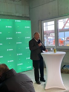 Helmut Peter steht vor einem gr&uuml;nem Dekra-Banner und spricht ins Mikrofon
