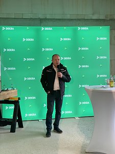 Mario Voigt steht vor gr&uuml;nem Dekra Banner und spricht ins Mikrofon.