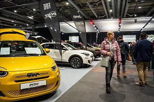 Gelber Fiat auf einer Automesse, flankiert von weiteren Fahrzeugen und Besucherinnen und Besuchern in einer großen Messehalle.