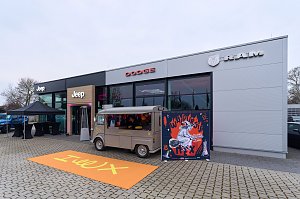 Autohaus mit Jeep-, Dodge- und RAM-Showroom, davor Foodtruck und Eventposter Hex.