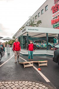 �koda Roadshow Bühne mit einem bunt beklebten Fahrzeug; davor 2 Besucher, die ein Wurfspiel spielen.