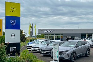 Außenansicht des Autohauses Peter in Halle Neustadt/ Göttinger Bogen mit einer großen Markensäule für Opel, Peugeot, Citroën und Fiat im Vordergrund sowie mehreren ausgestellten Fahrzeugen auf dem Parkplatz. Im Hintergrund ist das Autohaus.