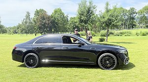 Schwarze Mercedes-Benz Limousine wird auf dem Golfplatz präsentiert, zwei Personen stehen daneben.