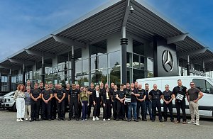 Das Service-Team aus Dessau steht vor dem Mercedes-Benz Center. Zwei Kollegen halten die Auszeichnung in den Händen. Im Hintergrund sind Autos zu sehen.