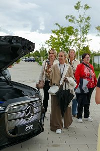 Mehrere Frauen, die im Freien hinter dem geöffneten Frunk eines Mercede-Benz GLC stehen und das Auto betrachten.