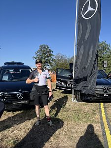 Serviceberater Robert Spaeth im Sportoutfit am Ausstellungsstand. Er steht lächelnd mit Daumen nach oben zwischen zwei Fahrzeugen.