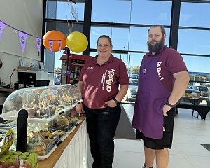 Zwei Personen vom HAPPINO Freizeit- und Erlebnis-Center stehen hinter einem Verkaufsstand mit Kuchen und S&uuml;&szlig;igkeiten.